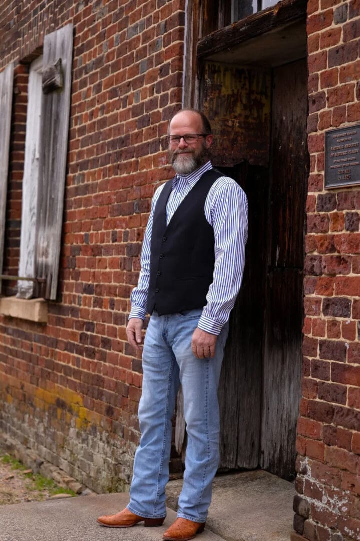 A man standing in front of a brick building.