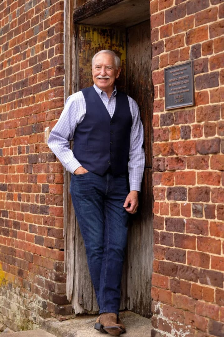 A man standing in front of a brick wall.