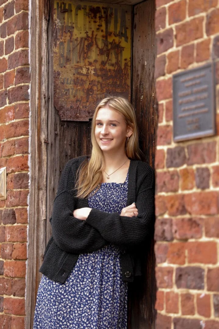 A woman standing in front of a brick wall.