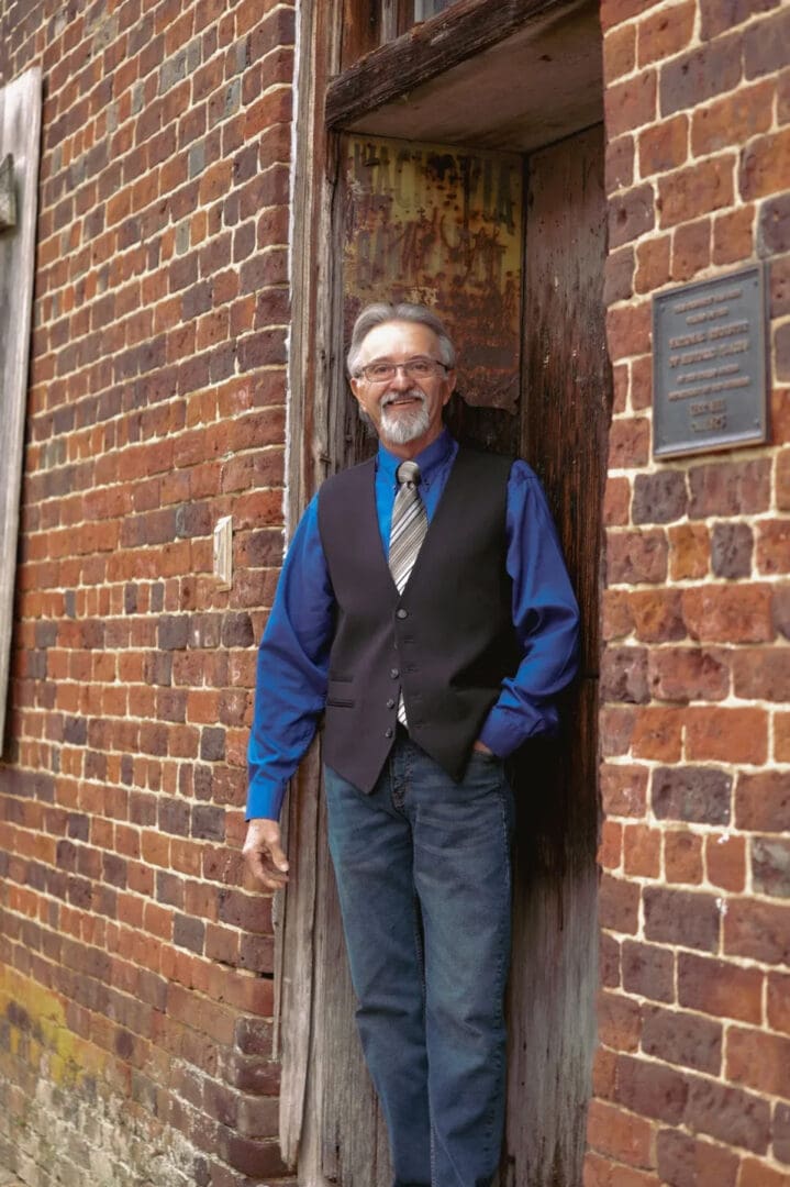 A man standing in front of a brick building.