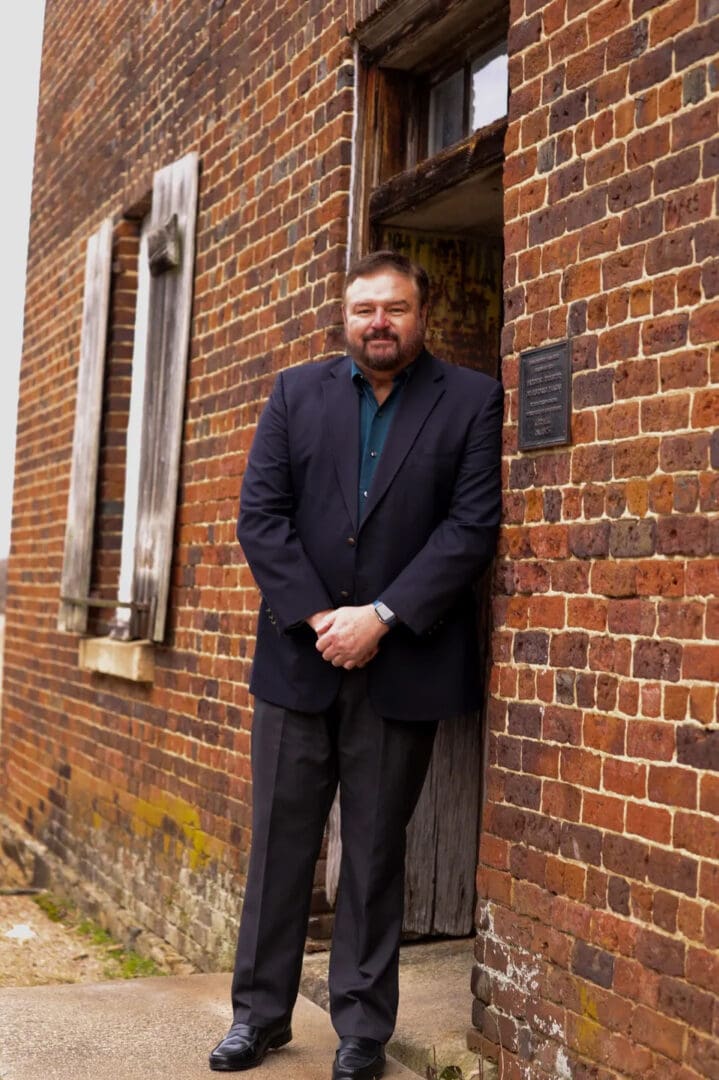 A man standing in front of a brick building.